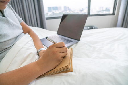 Cropped view of Businessman writing on notebook in the bedroomの写真素材