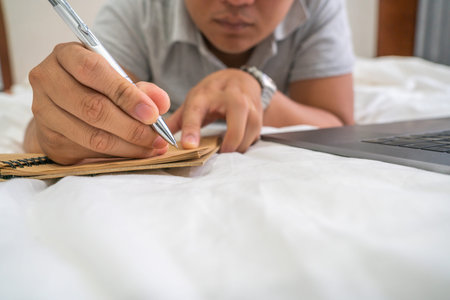 Close up of young man writing on notebook