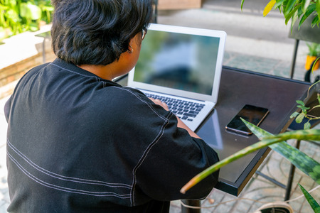 Rear view of Asian girl using laptop in the gardenの写真素材