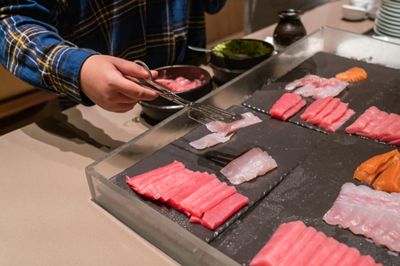Woman hand choosing Sashimi in the luxury buffetの写真素材