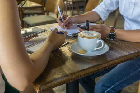 Female and male hands holding smartphone and writing note