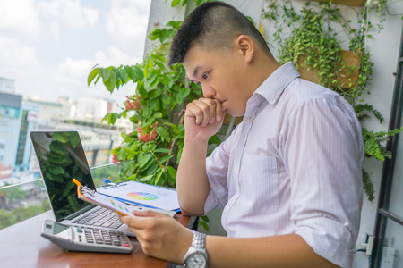 Asian business manager reading financial reports and thinkingの写真素材