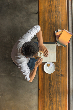 Asian man reading books and drinking hot coffeeの写真素材