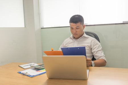 Asian businessman reading financial reports to understand more about current business situationの写真素材