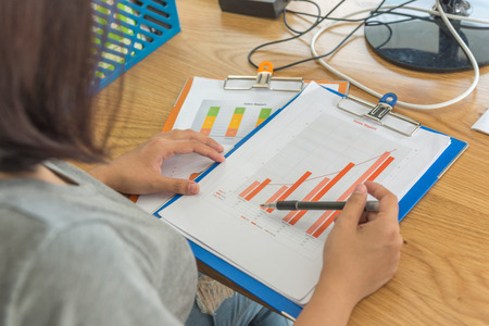 Young Asian office employee analyzing financial number on sales reportの写真素材