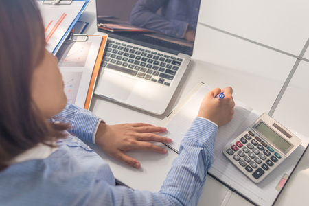 Young Asian office woman writing note in the business roomの写真素材