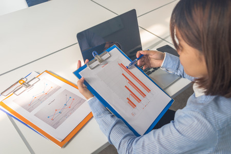 Young businesswoman in blue shirt reading financial reports in the business officeの写真素材