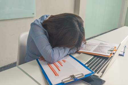 Tired businesswoman accountant sleeping with bills and paper folders in the business officeの写真素材