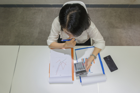 High angle view of sales manager using calculator and thinkingの写真素材