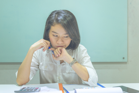 Young Asian woman reading financial reports and thinkingの写真素材