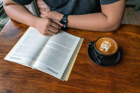 Young man read a book and drink coffeeの写真素材