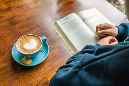 Woman hand reading book and drinking coffee