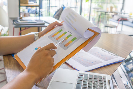 Asian employee checking sales report in office room