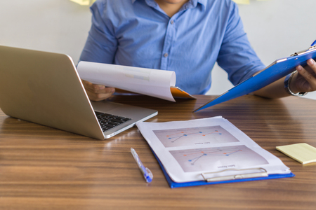 Businessman in blue shirt checking financial documentsの写真素材