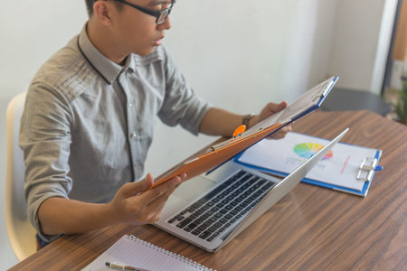 Young man reading report document at workplace