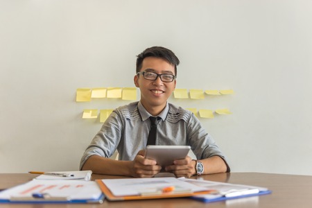 Smiling office man holding tablet in the officeの写真素材