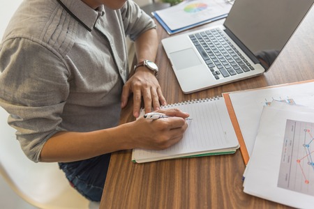 Young office man writing notes on wooden tableの写真素材