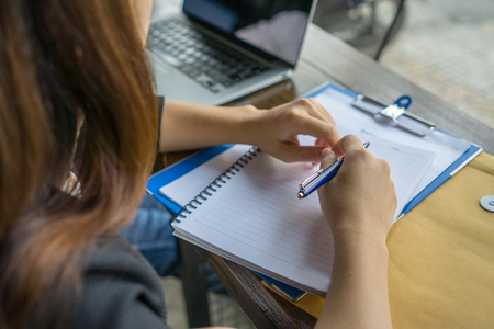 Young woman writing notes in the officeの写真素材