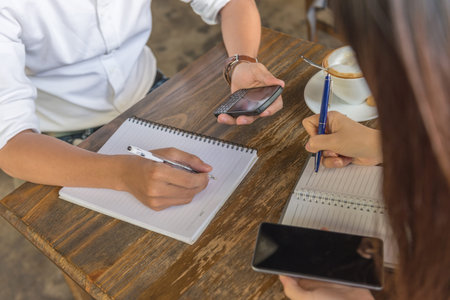 Female and male hands holding phone and writing note