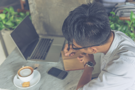 Asian man writing notes in the coffee shopの写真素材
