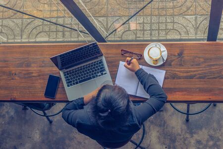 Top view of freelancer working on laptop and writing notesの写真素材