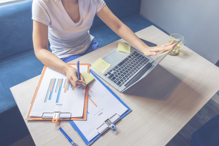Close up of woman working on laptop and business chart document