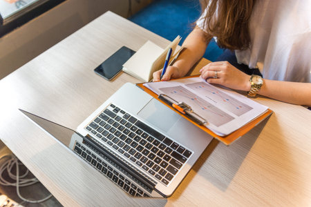 Woman working with sales chart data and laptop on table
