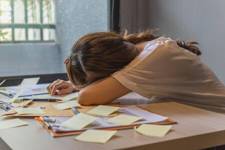 Exhausted woman sleeping on desk with many sticky noteの写真素材
