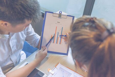 Close up of businessman and businesswoman discuss about sales reportの写真素材