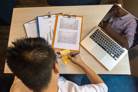 High angle view of Asian man writing sticky noteの写真素材