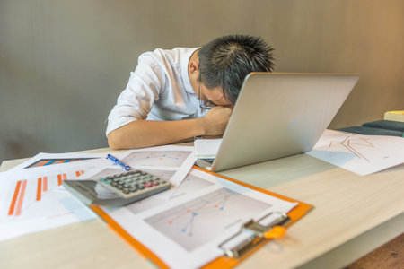 Exhausted freelancer working on laptop and financial document