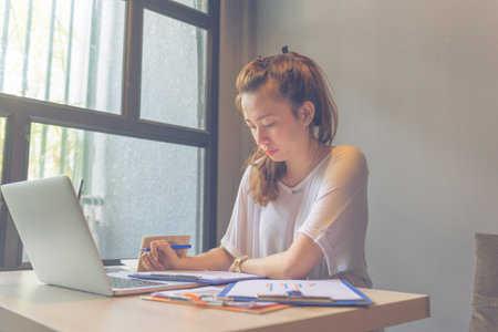 Beautiful lady working with folders and computer next to window