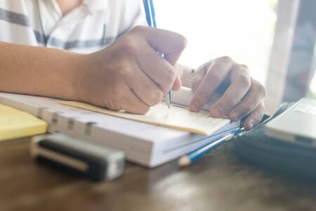 Closeup of student hand writing notebook when doing homeworkの写真素材