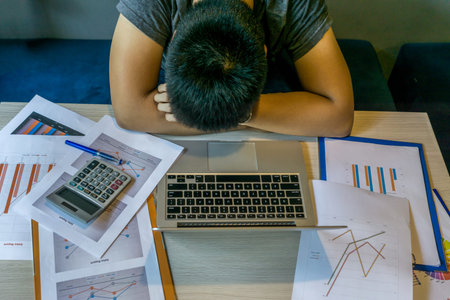 Exhausted millennial fall asleep on desk with laptop, unorganized document
