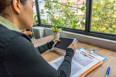 Woman using digital tablet at workplace next to windowの写真素材