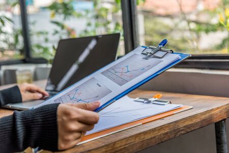 Closeup of woman hands holding sales report and using laptopの写真素材