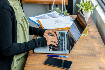 Closeup of woman hands typing laptop at rustic office table