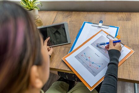 Top view of woman using tablet and pointing at diagramの写真素材