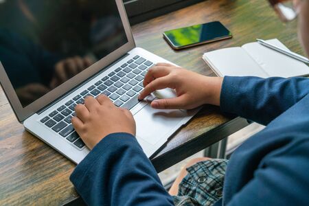 Asian woman typing laptop keyboard on rustic wooden tableの写真素材