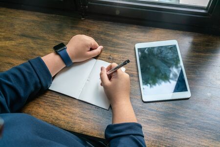 Females hand writing notes beside the digital tabletの写真素材