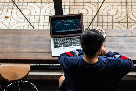 Young Asian businesspeople working on financial candlestick graph on laptopの写真素材
