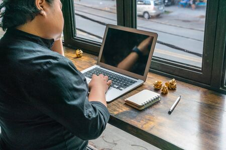 Lesbian using laptop with crumpled papers ball on rustic tableの写真素材