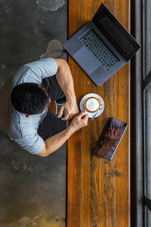 Vertical photo of muscled freelancer using laptop and drinking coffeeの写真素材