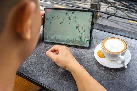 Rear view of Asian businessman looking candlestick graph on tablet