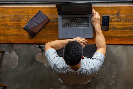 Asian muscled male freelancer working on laptop at rustic coffeeshopの写真素材
