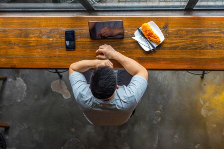 Top view of Asian businessman using tablet at wooden tableの写真素材