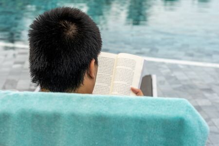 Closeup of human reading book at swimming poolの写真素材