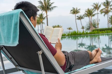 Relaxing and reading book at beautiful tropical swimming poolの写真素材