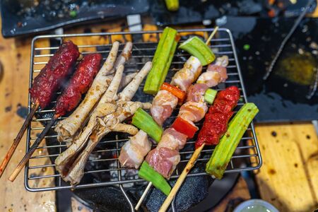 Assortment of grilled skewers and meat on charcoal stoveの写真素材