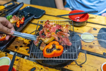 Grilled meat and bell pepper on smoky charcoal stoveの写真素材